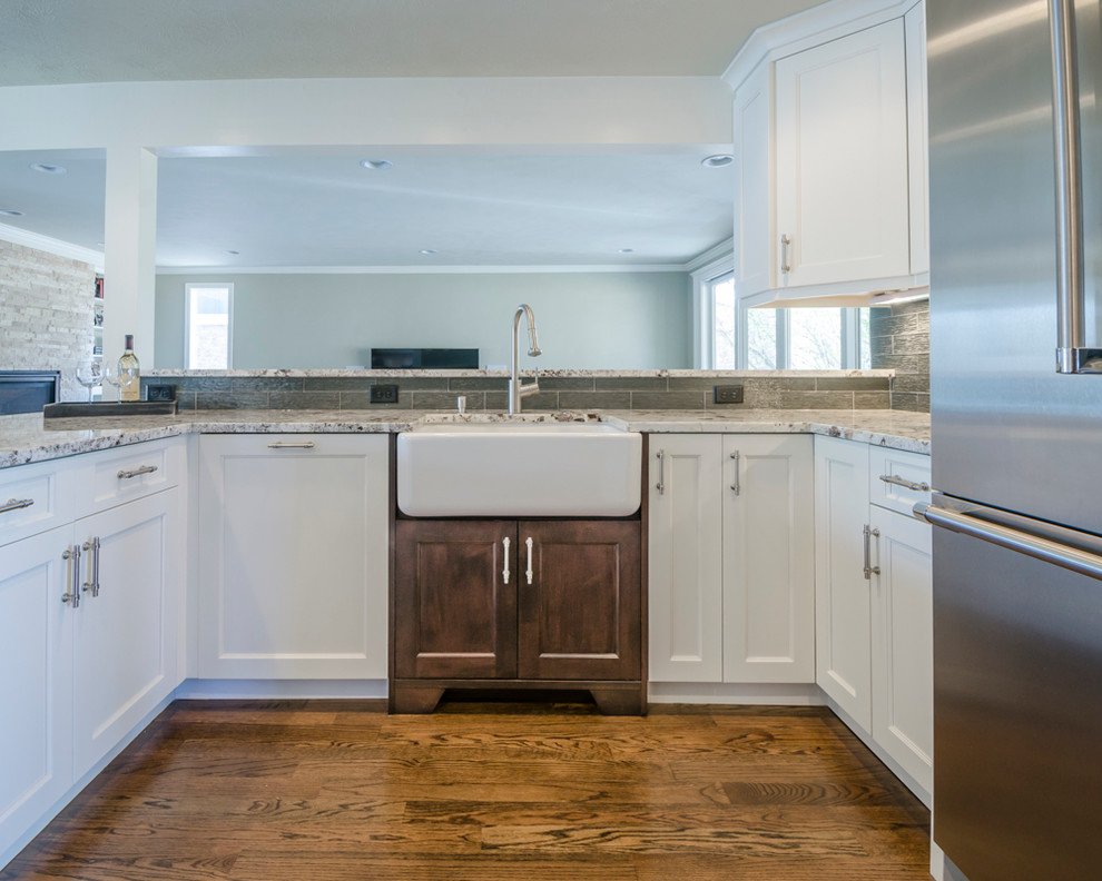 Example of a mid-sized transitional u-shaped medium tone wood floor eat-in kitchen design in Denver with a farmhouse sink, shaker cabinets, white cabinets, laminate countertops, green backsplash, glass tile backsplash, stainless steel appliances and a peninsula