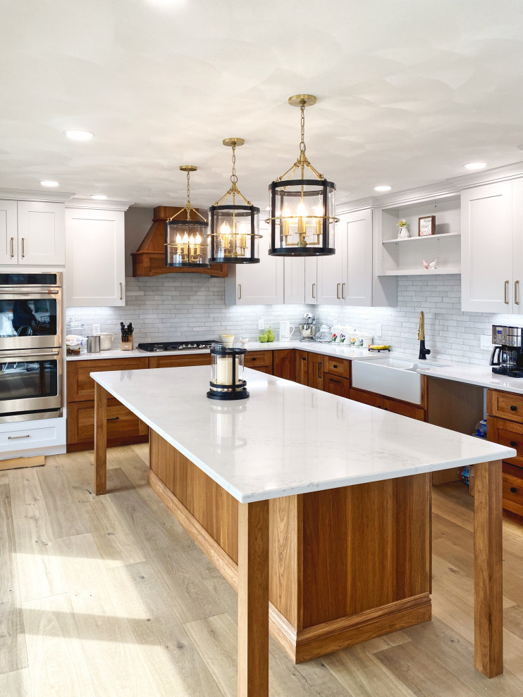 Large transitional light wood floor and beige floor kitchen photo in Chicago with a farmhouse sink, recessed-panel cabinets, medium tone wood cabinets, quartz countertops, gray backsplash, stone tile backsplash, stainless steel appliances, an island and white countertops