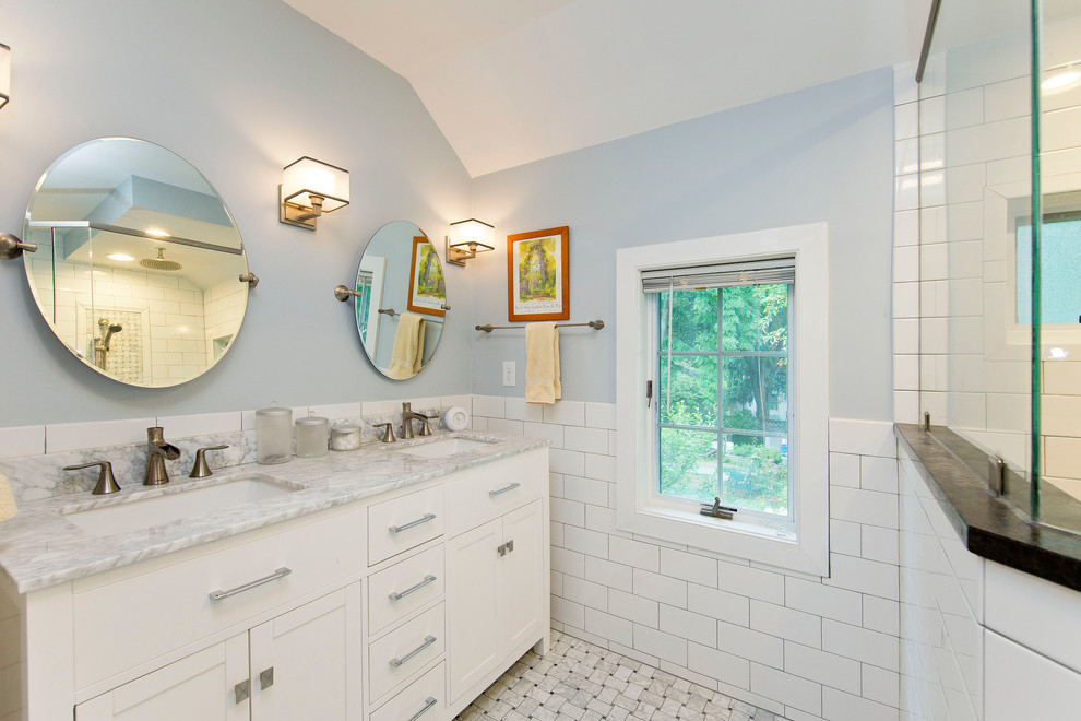 This is an example of a mid-sized transitional master bathroom in DC Metro with shaker cabinets, white cabinets, a corner shower, a one-piece toilet, white tile, ceramic tile, blue walls, marble floors, an undermount sink, marble benchtops, white floor and a hinged shower door.
