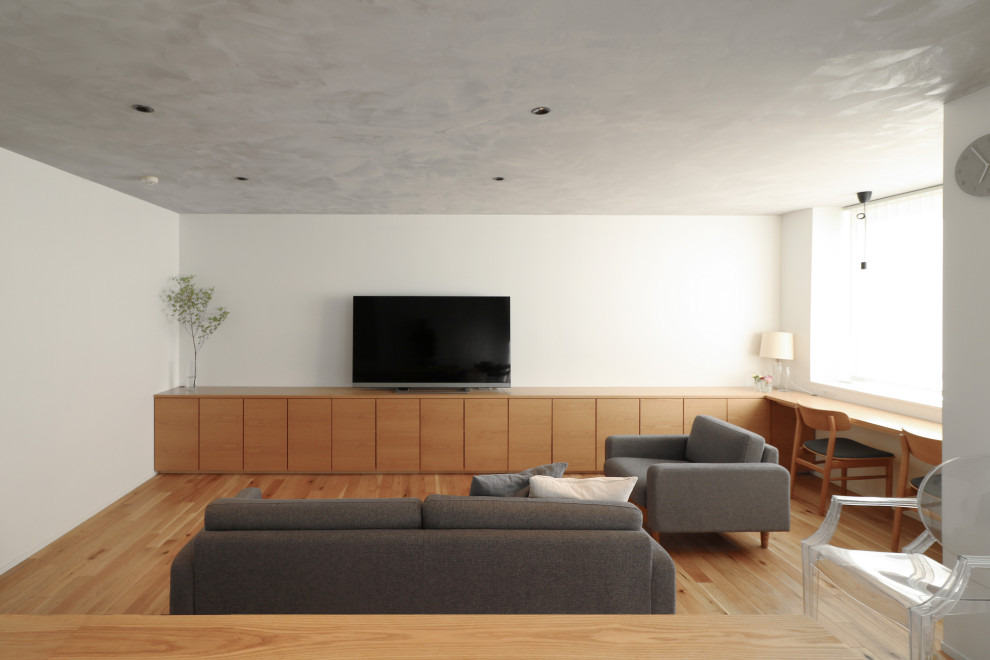 На фото: открытая гостиная комната в современном стиле с белыми стенами, паркетным полом среднего тона и отдельно стоящим телевизором с