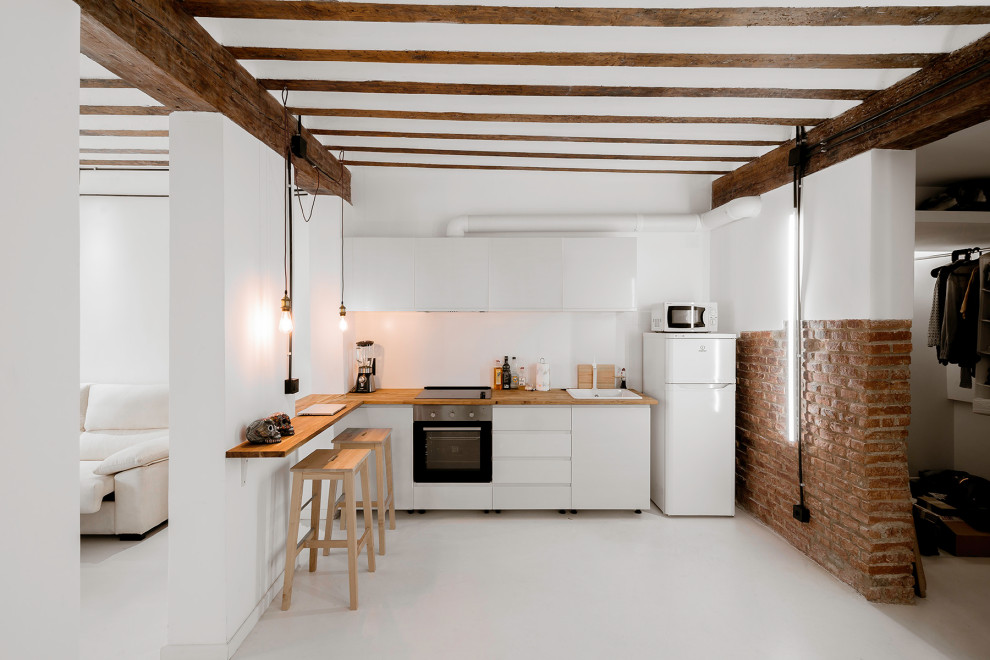 Design ideas for a mid-sized industrial l-shaped open plan kitchen in Madrid with an undermount sink, brown splashback, timber splashback, white appliances, with island, white floor, brown benchtop and exposed beam.