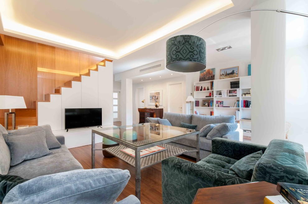Inspiration for a mid-sized contemporary open concept living room in Seville with a library, white walls, dark hardwood floors, no fireplace and a freestanding tv.