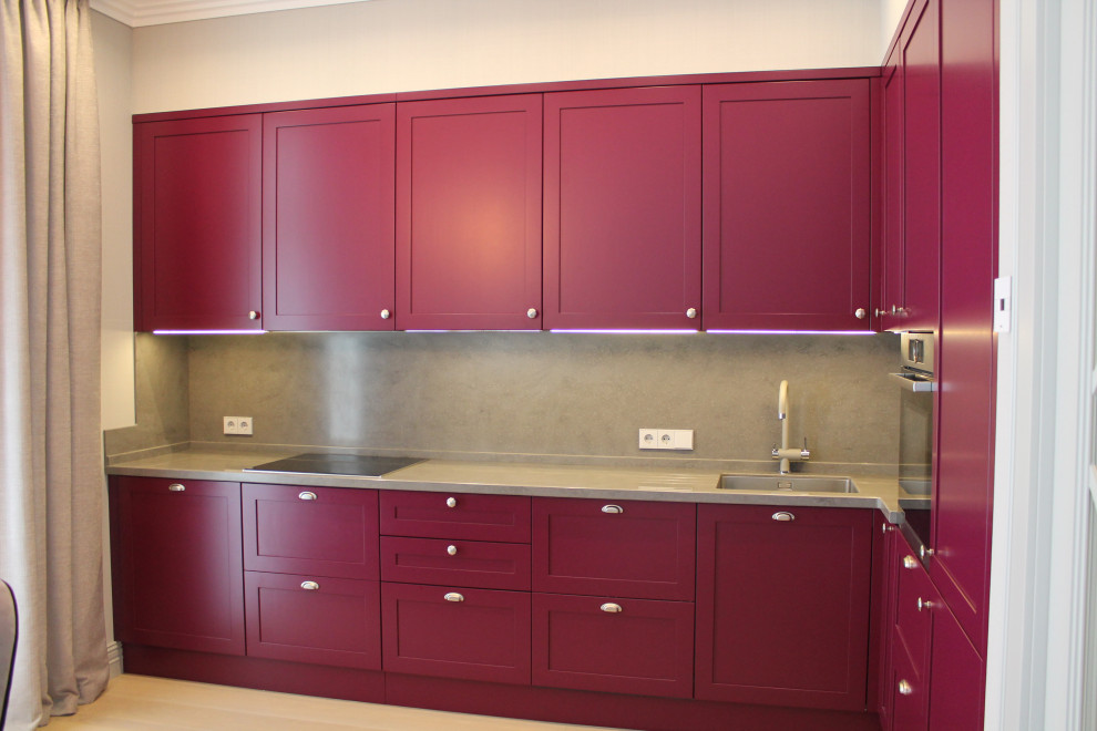Photo of a mid-sized modern l-shaped eat-in kitchen in Moscow with an undermount sink, recessed-panel cabinets, pink cabinets, solid surface benchtops, grey splashback, stone slab splashback, panelled appliances, laminate floors, no island, brown floor and grey benchtop.