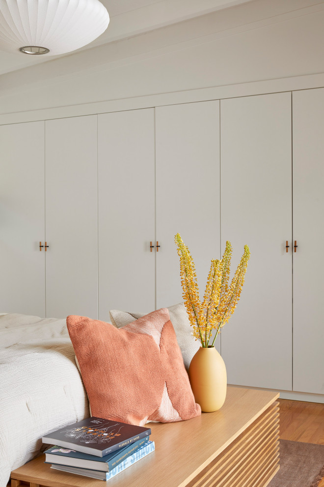 Ejemplo de dormitorio principal vintage de tamaño medio con paredes blancas, suelo de madera en tonos medios, suelo marrón y vigas vistas