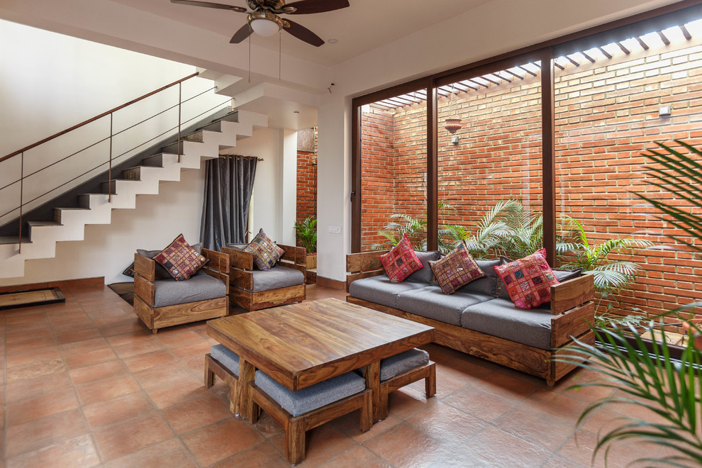 Asian formal living room in Bengaluru with white walls, brown floor and brick floors.