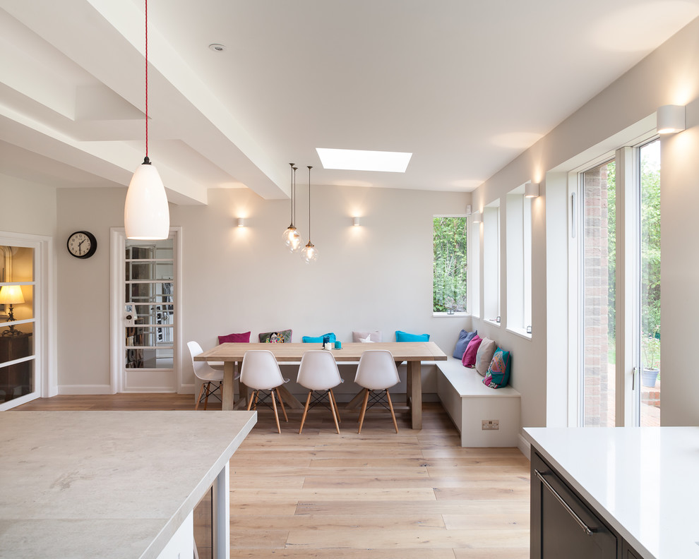 This is an example of a large contemporary l-shaped kitchen/diner in London with a built-in sink, flat-panel cabinets, grey cabinets, concrete worktops, integrated appliances, medium hardwood flooring and a breakfast bar.