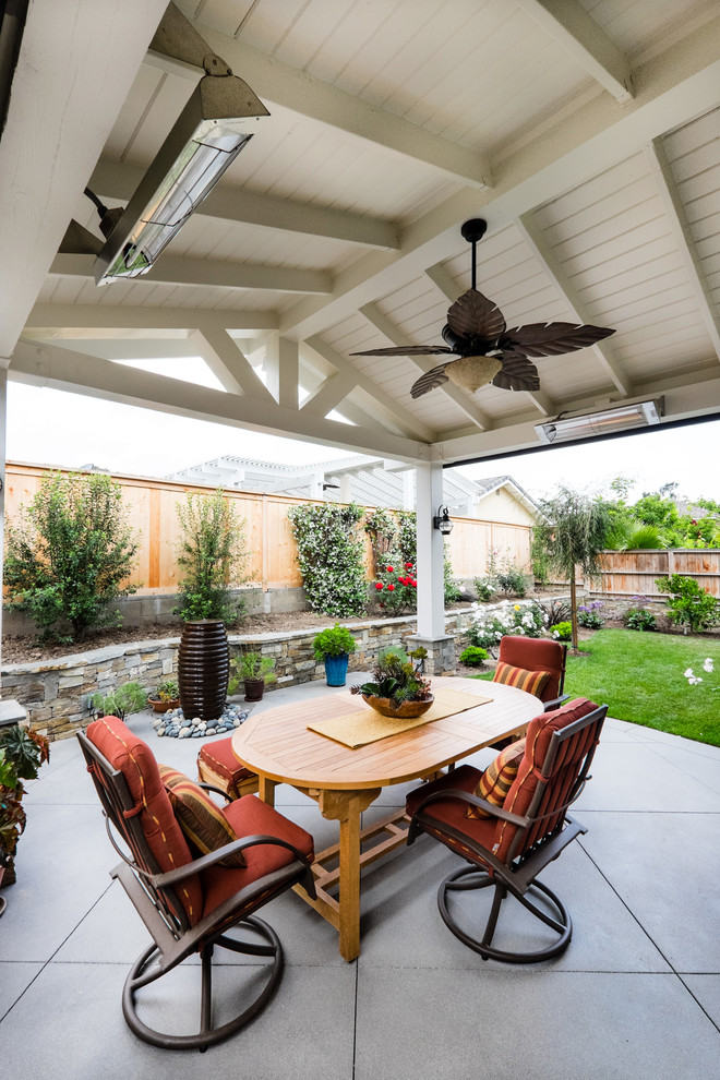Inspiration for a mid-sized traditional backyard patio in Orange County with concrete slab, a roof extension and a water feature.