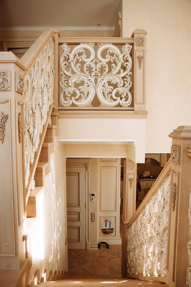 На фото: большая п-образная деревянная лестница в классическом стиле с деревянными ступенями, деревянными перилами, обоями на стенах и кладовкой или шкафом под ней с