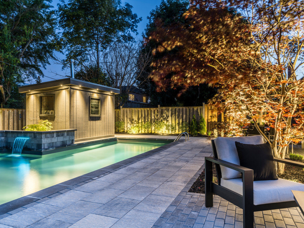 Mid-sized transitional backyard concrete paver and l-shaped lap pool fountain photo in Toronto