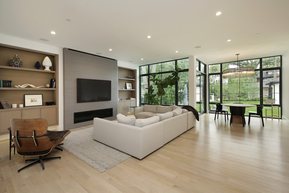 Inspiration for a large modern open concept living room in Chicago with white walls, light hardwood floors, a standard fireplace, a tile fireplace surround and a wall-mounted tv.