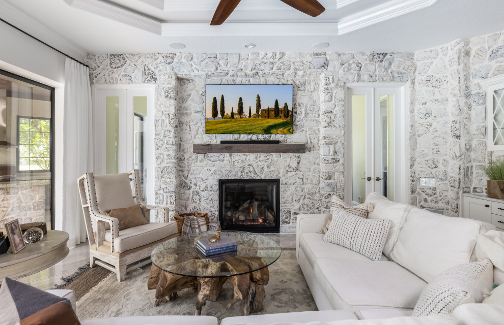 This is an example of an expansive mediterranean open concept family room in Tampa with a game room, white walls, porcelain floors, a two-sided fireplace, a stone fireplace surround, a freestanding tv, grey floor, coffered and brick walls.