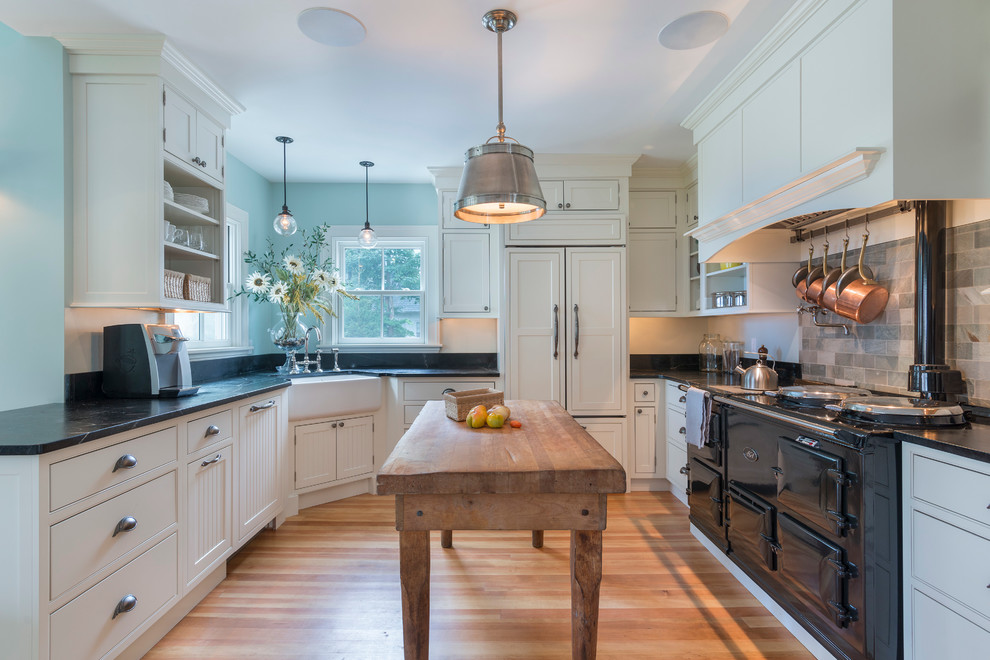 Design ideas for a traditional u-shaped separate kitchen in Providence with a farmhouse sink, flat-panel cabinets, white cabinets, black appliances, light hardwood floors and with island.