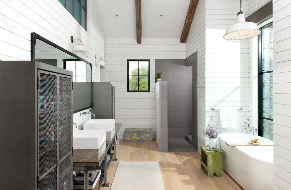 Inspiration for an expansive country master bathroom in Other with open cabinets, grey cabinets, a freestanding tub, an open shower, gray tile, stone tile, white walls, light hardwood floors, a vessel sink, solid surface benchtops and an open shower.