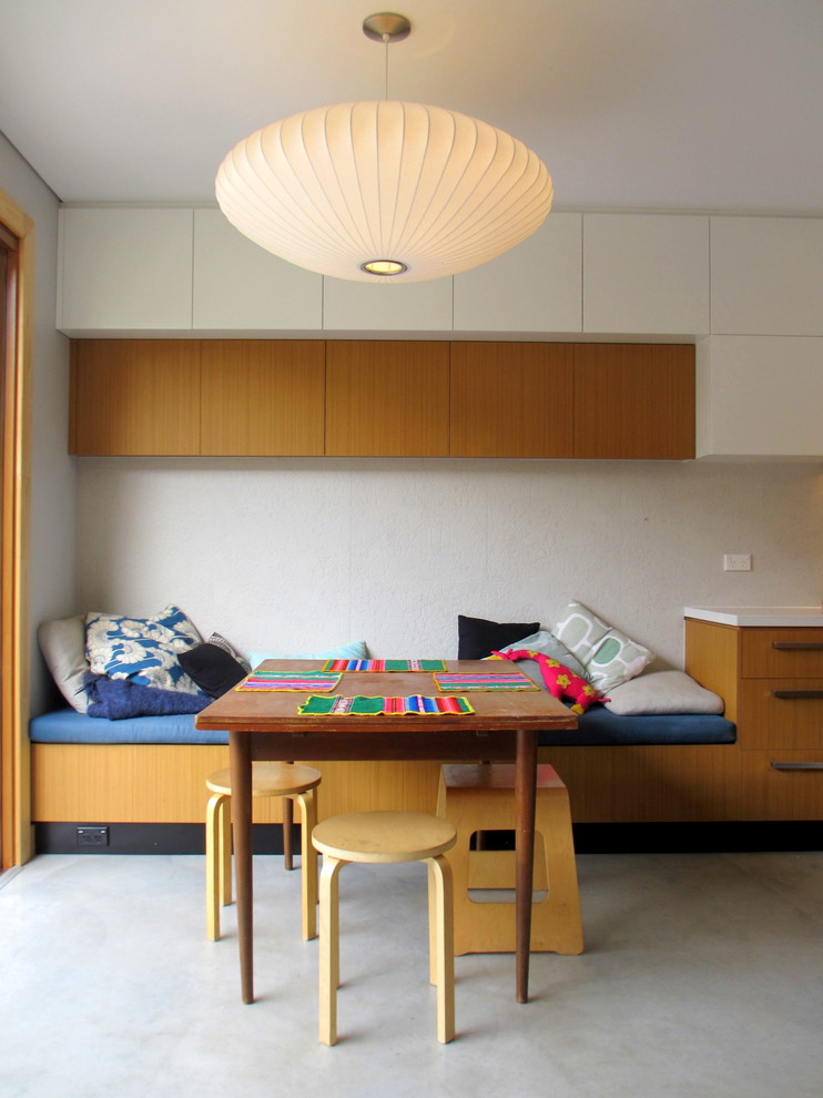 Modern single-wall eat-in kitchen in Sydney with white splashback, stainless steel appliances, white walls, concrete floors and with island.