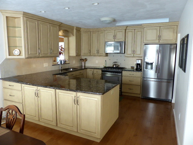 Example of a mid-sized mountain style u-shaped light wood floor eat-in kitchen design in New York with an undermount sink, raised-panel cabinets, beige cabinets, quartz countertops, ceramic backsplash, stainless steel appliances, a peninsula and beige backsplash