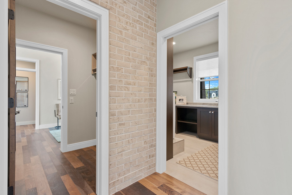 Hallway - transitional medium tone wood floor and brick wall hallway idea with gray walls