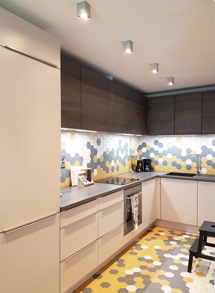 This is an example of a mid-sized modern l-shaped eat-in kitchen in Dublin with a double-bowl sink, flat-panel cabinets, dark wood cabinets, laminate benchtops, multi-coloured splashback, porcelain splashback, black appliances, porcelain floors, a peninsula and multi-coloured floor.