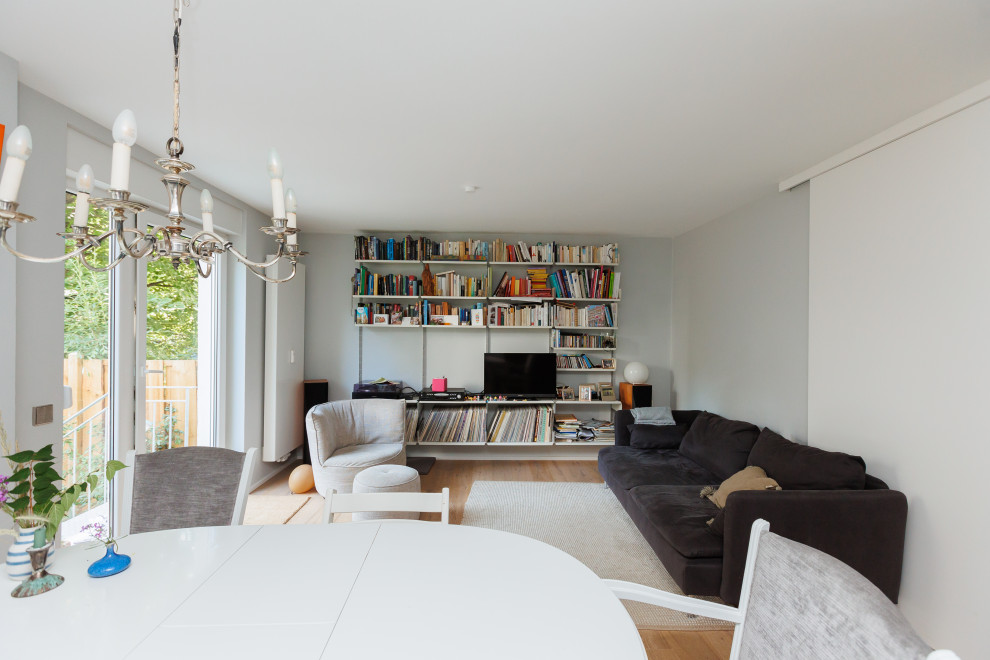 Photo of a contemporary open concept family room in Frankfurt with white walls, a corner tv and brown floor.