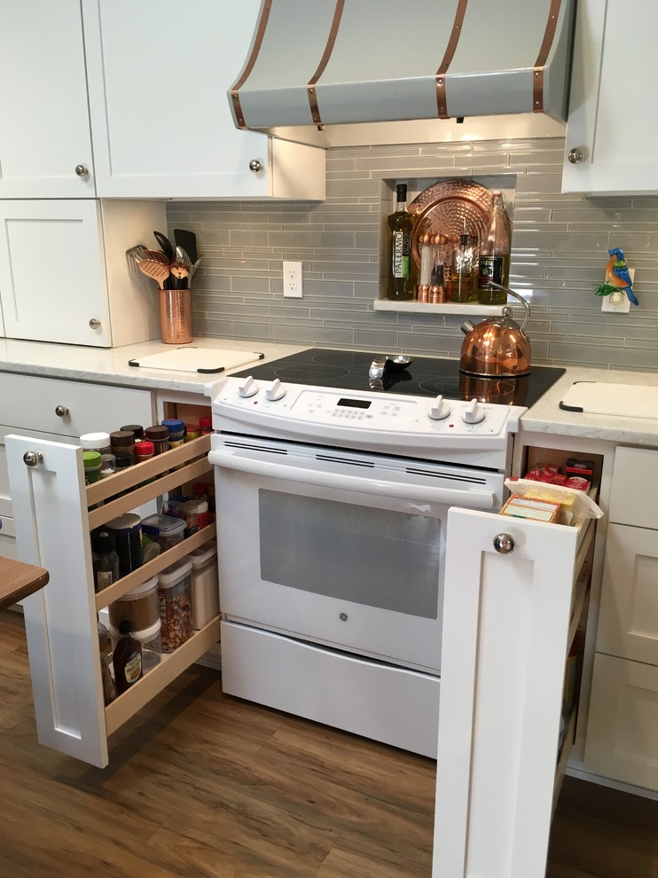 Mid-sized transitional u-shaped vinyl floor enclosed kitchen photo with an undermount sink, shaker cabinets, white cabinets, quartz countertops, gray backsplash, glass tile backsplash, white appliances and no island