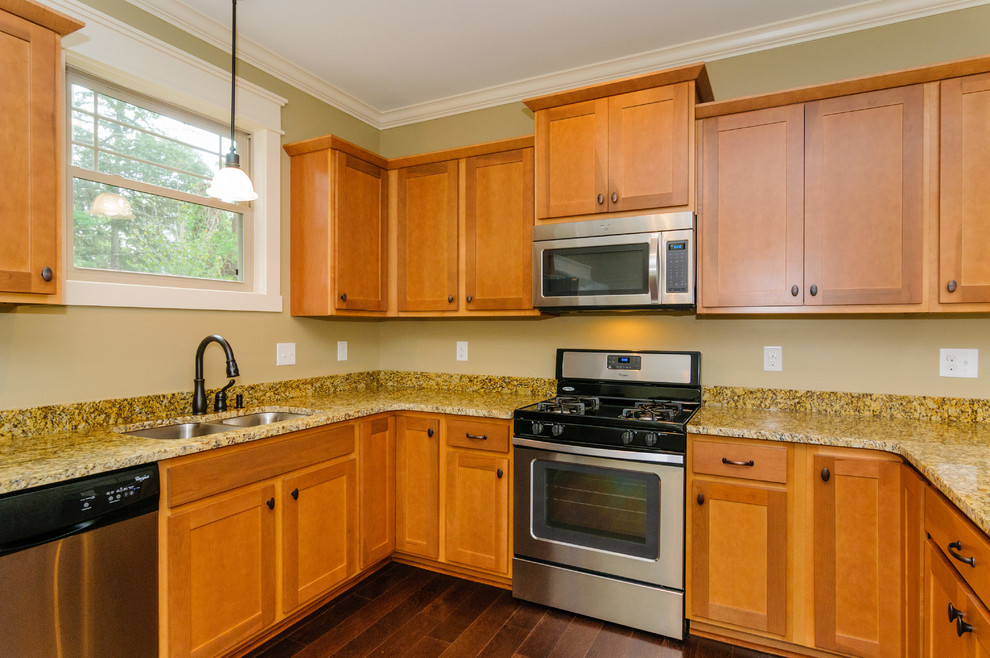 Large transitional u-shaped dark wood floor eat-in kitchen photo with a double-bowl sink, raised-panel cabinets, light wood cabinets, soapstone countertops, beige backsplash, stainless steel appliances and no island