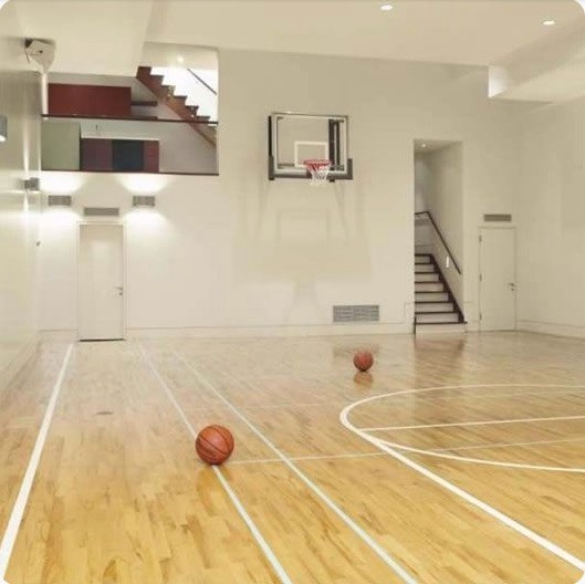 Large eclectic indoor sport court in Los Angeles with beige walls and light hardwood floors.