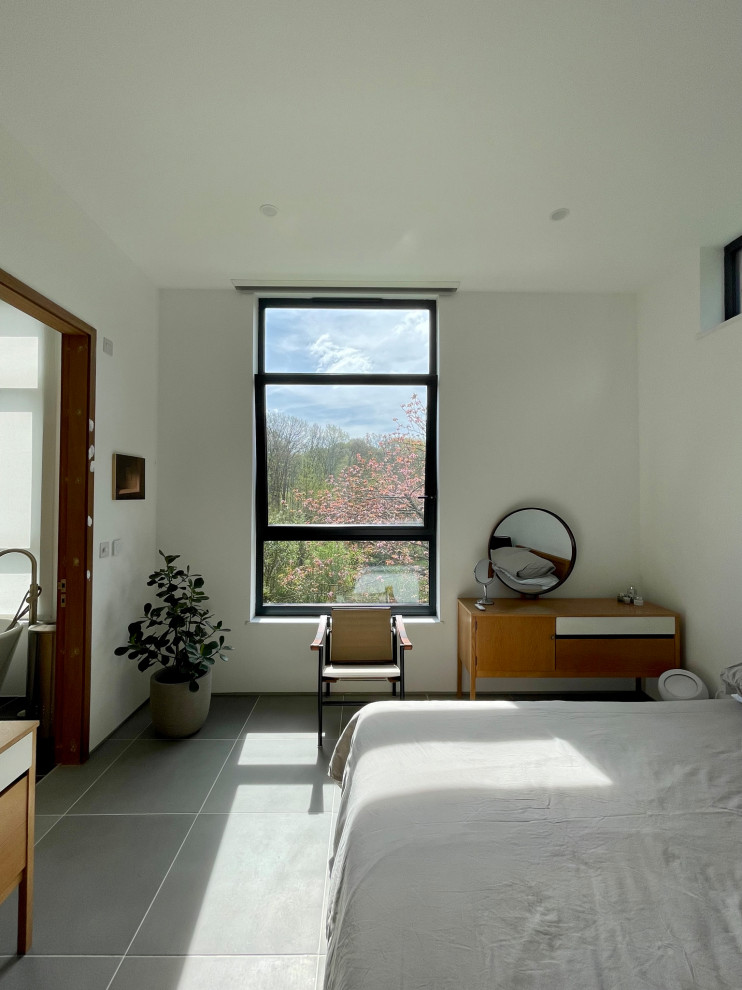 Exemple d'une chambre d'amis tendance de taille moyenne avec un mur blanc, un sol en carrelage de céramique et un sol gris.