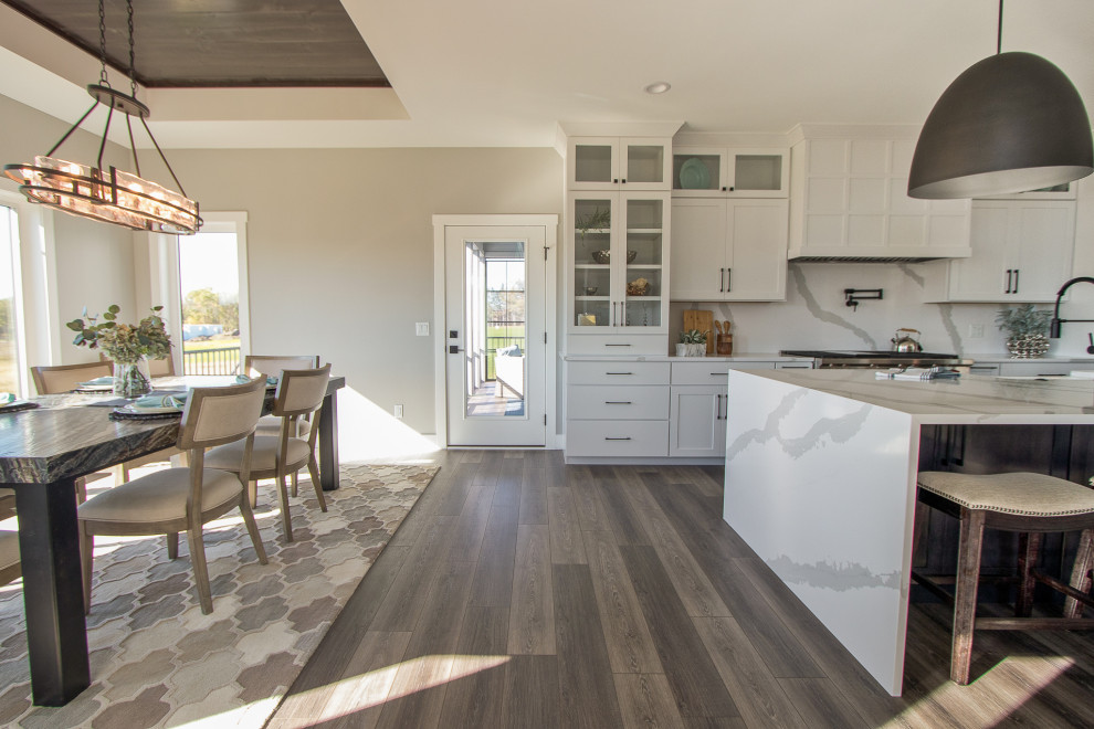 Inspiration for a transitional vinyl floor and brown floor open concept kitchen remodel with recessed-panel cabinets, white cabinets, quartz countertops, white backsplash, stone slab backsplash, stainless steel appliances, an island and white countertops