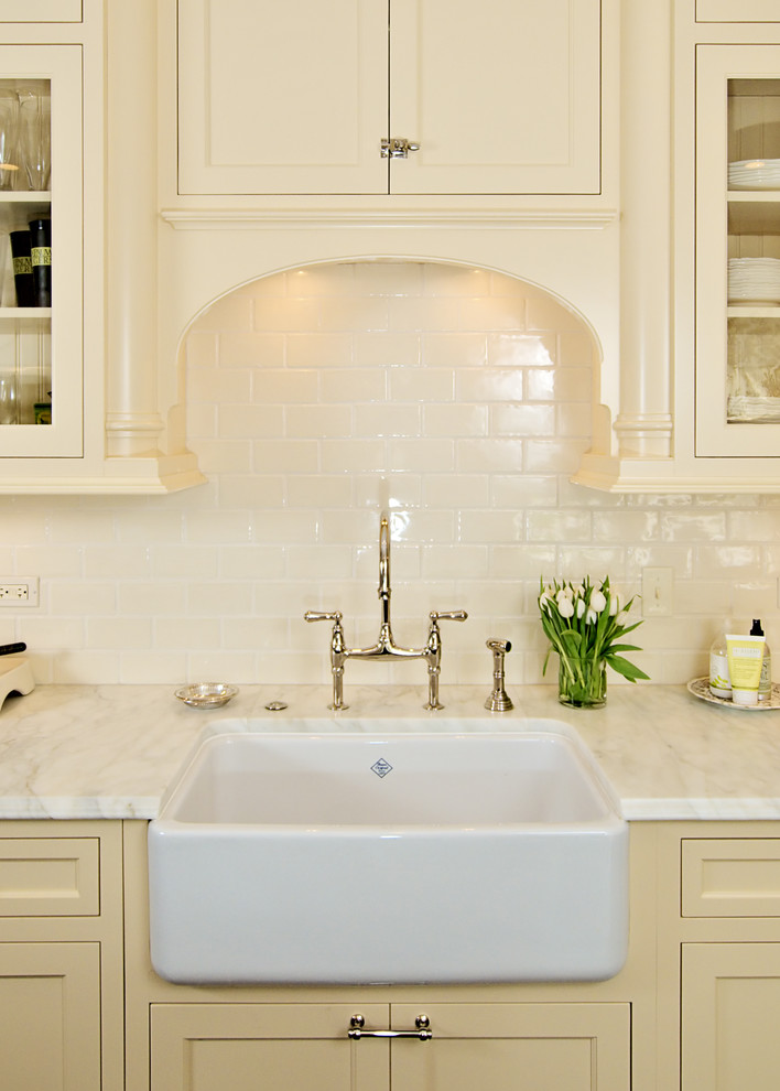 Inspiration for a mid-sized transitional kitchen remodel in Chicago with a farmhouse sink, glass-front cabinets, white cabinets, white backsplash, subway tile backsplash and granite countertops