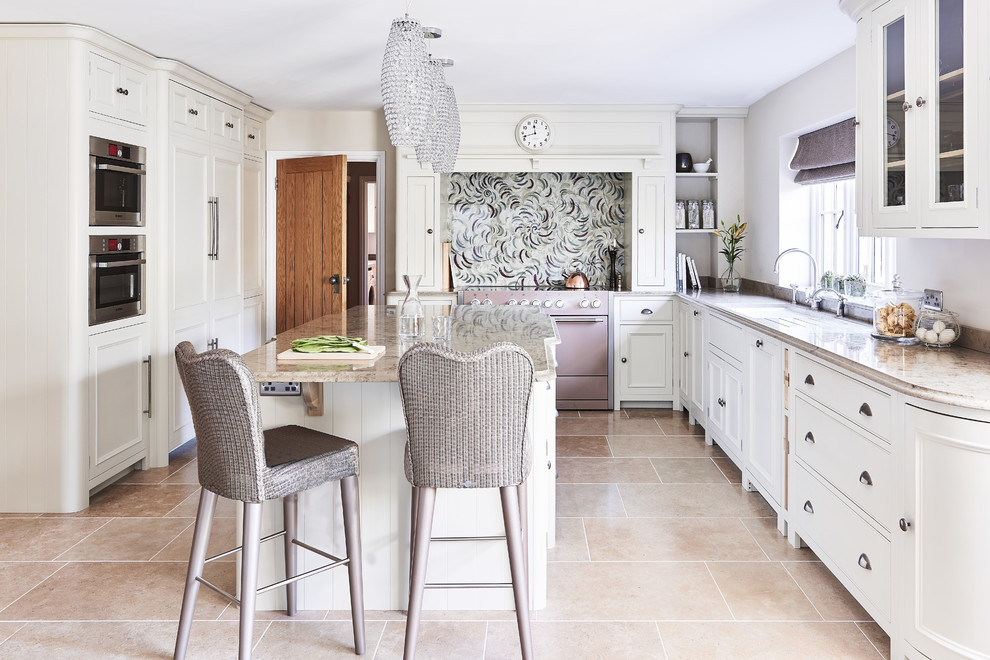 This is an example of a large traditional u-shaped eat-in kitchen in Berkshire with a farmhouse sink, shaker cabinets, white cabinets, limestone benchtops, multi-coloured splashback, glass sheet splashback, coloured appliances, limestone floors and with island.