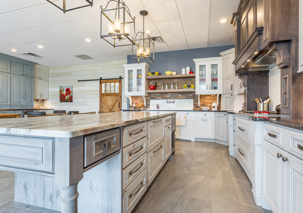 Eat-in kitchen - large transitional l-shaped porcelain tile and brown floor eat-in kitchen idea with raised-panel cabinets, white cabinets, marble countertops, brown backsplash, an island, stone tile backsplash, stainless steel appliances and a drop-in sink
