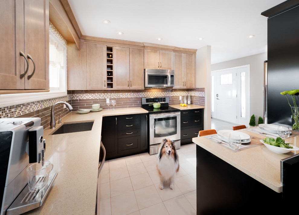 Inspiration for a mid-sized transitional u-shaped ceramic tile eat-in kitchen remodel in Ottawa with an undermount sink, shaker cabinets, black cabinets, quartz countertops, beige backsplash, glass tile backsplash, stainless steel appliances and a peninsula
