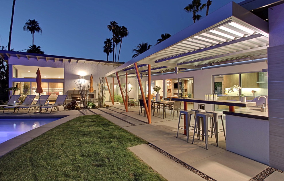 Design ideas for a large midcentury backyard patio in Other with concrete pavers, an awning and an outdoor kitchen.