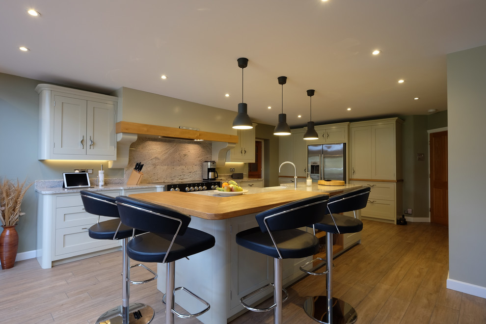 This is an example of a large contemporary l-shaped open plan kitchen in Surrey with a farmhouse sink, shaker cabinets, green cabinets, granite benchtops, multi-coloured splashback, stone slab splashback, stainless steel appliances, porcelain floors, with island, multi-coloured floor and grey benchtop.