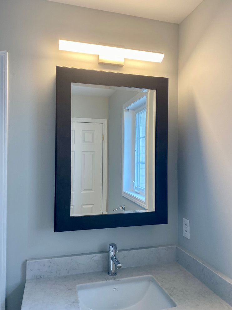 Inspiration for a transitional 3/4 porcelain tile, gray floor and single-sink bathroom remodel with recessed-panel cabinets, a one-piece toilet, gray walls, an undermount sink, quartzite countertops, white countertops and a built-in vanity