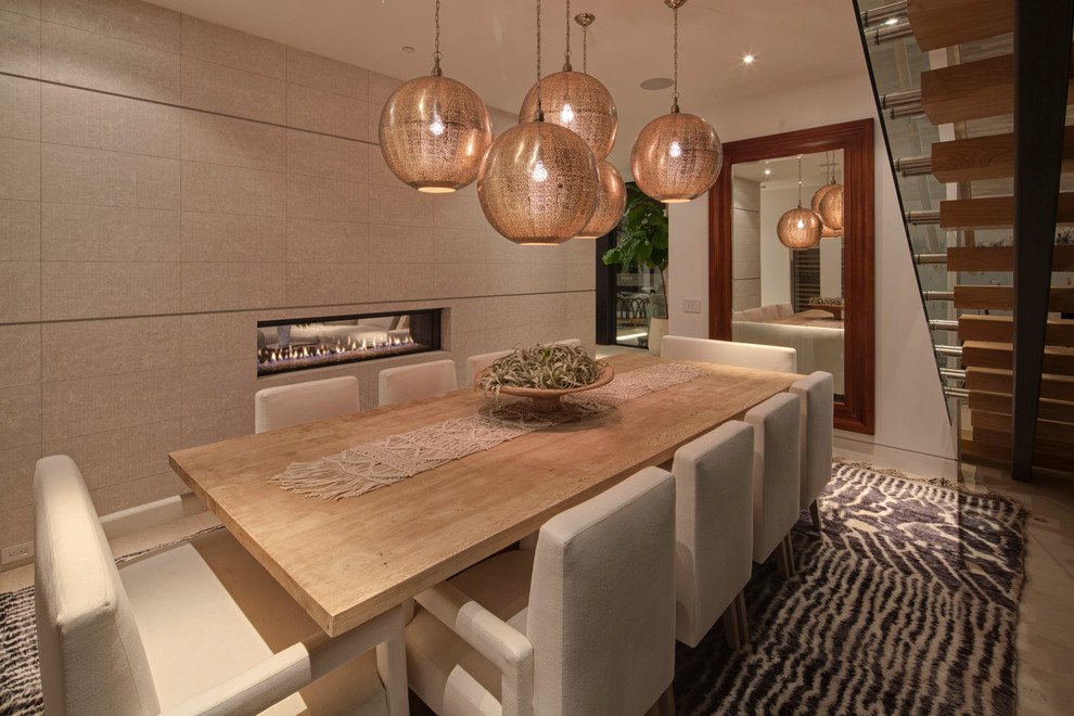 Mid-sized trendy light wood floor enclosed dining room photo in Los Angeles with a two-sided fireplace, beige walls and a tile fireplace