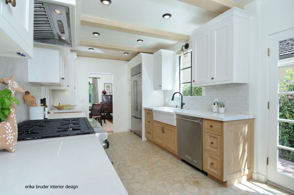 This is an example of a mid-sized galley open plan kitchen in Los Angeles with a farmhouse sink, raised-panel cabinets, white cabinets, white splashback, ceramic splashback, white appliances, cement tiles, no island and yellow floor.
