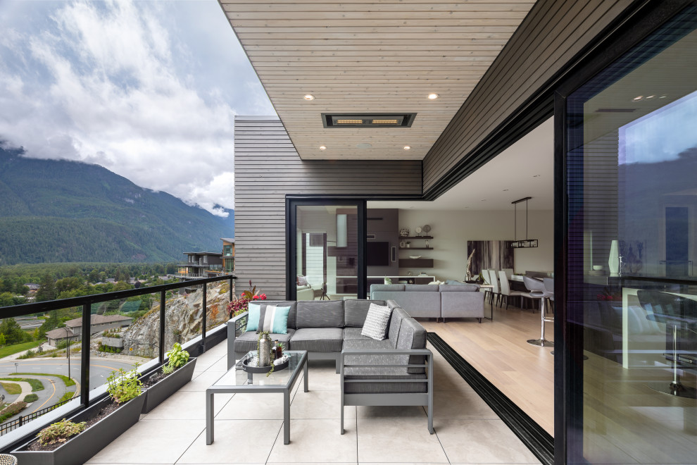 Réalisation d'une terrasse arrière et au premier étage minimaliste de taille moyenne avec une cheminée, une extension de toiture et un garde-corps en verre.