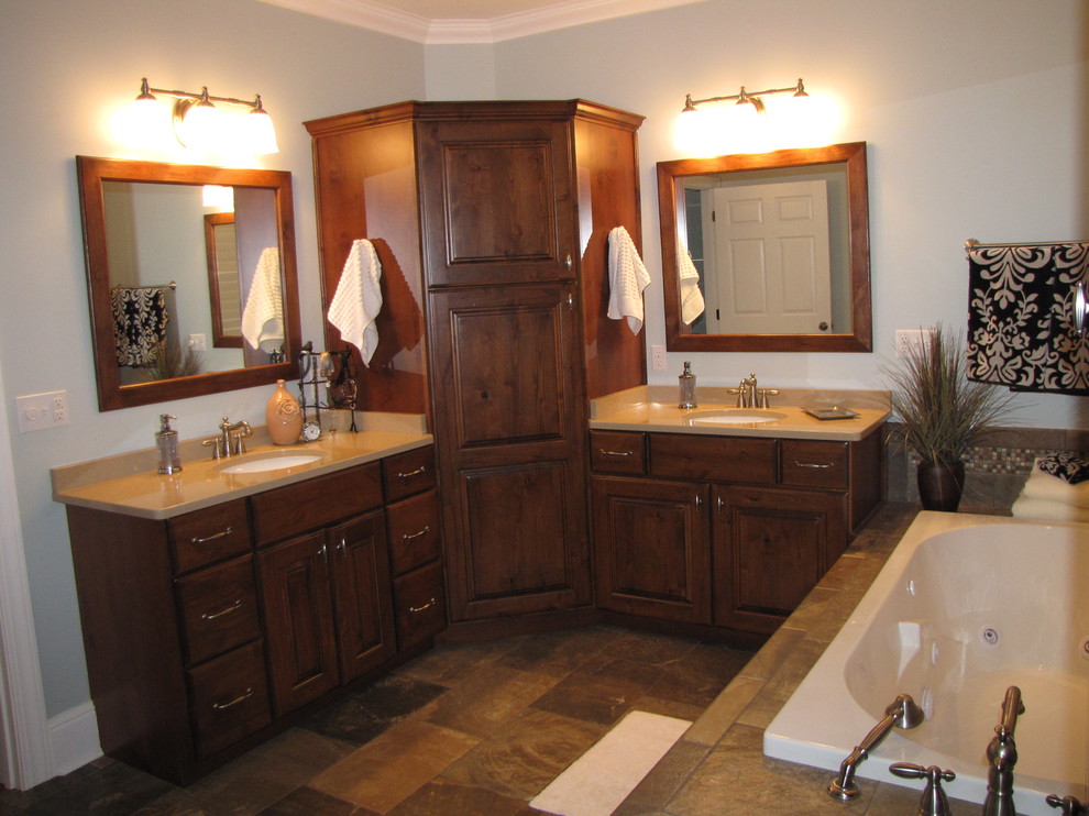 Photo of a mid-sized arts and crafts master bathroom in Nashville with an undermount sink, raised-panel cabinets, medium wood cabinets, engineered quartz benchtops, a drop-in tub, gray tile, porcelain tile, blue walls and porcelain floors.
