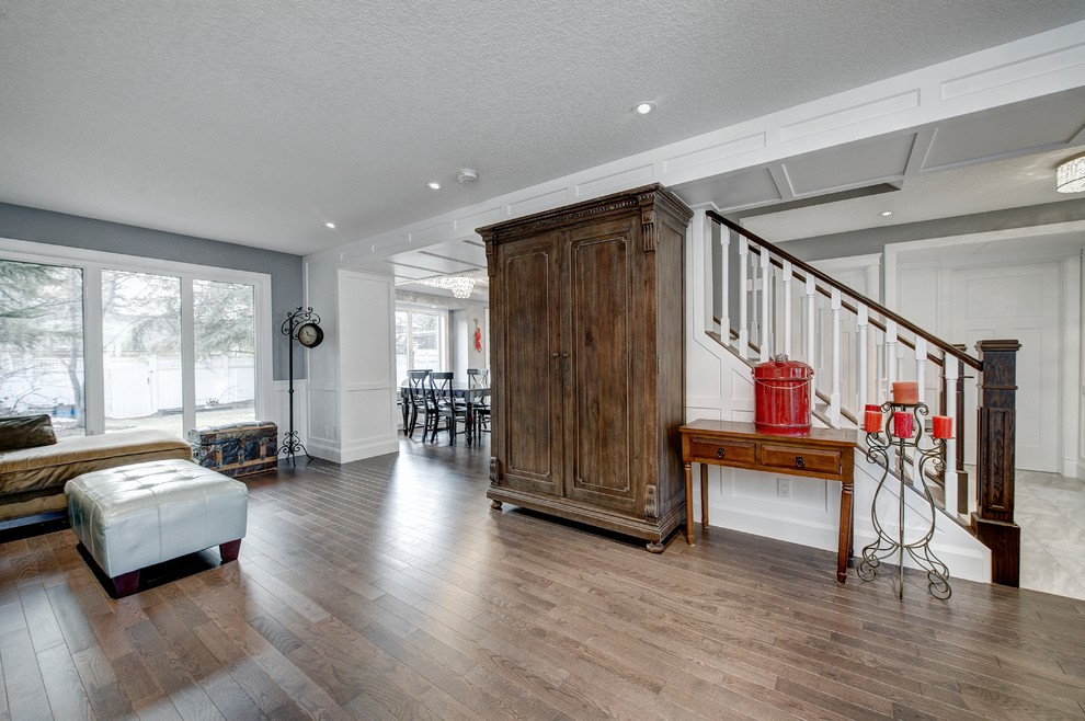 Inspiration for a mid-sized arts and crafts open concept family room in Calgary with a music area, grey walls, medium hardwood floors, a standard fireplace, a tile fireplace surround, no tv and brown floor.