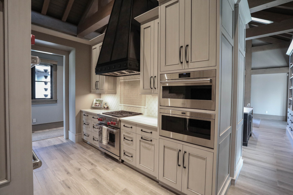Photo of an expansive traditional kitchen pantry in Other with beaded inset cabinets, beige cabinets, white splashback, ceramic splashback, ceramic floors, with island and exposed beam.