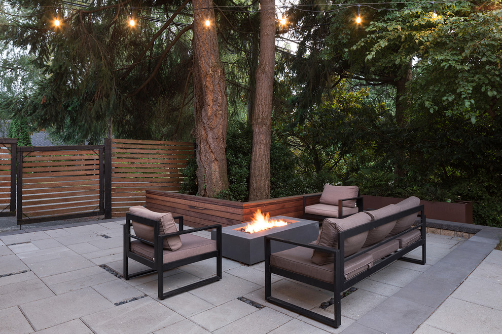 This is an example of a large midcentury backyard patio in Seattle with a fire feature, concrete pavers and no cover.