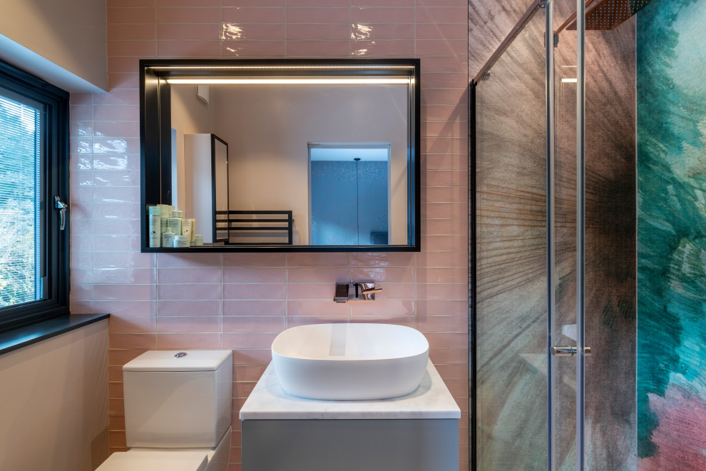 Inspiration for a mid-sized contemporary master bathroom in London with flat-panel cabinets, grey cabinets, an open shower, pink tile, ceramic floors, a sliding shower screen, a single vanity, a freestanding vanity and wallpaper.