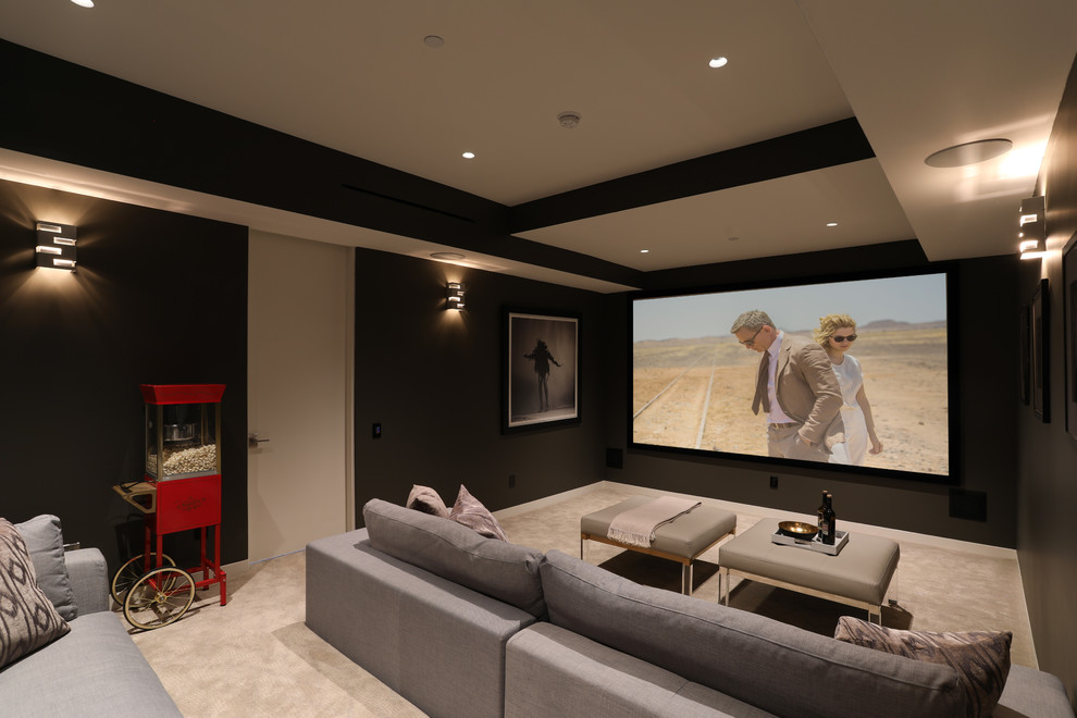 This is an example of a contemporary enclosed home theatre in Los Angeles with black walls, carpet and beige floor.