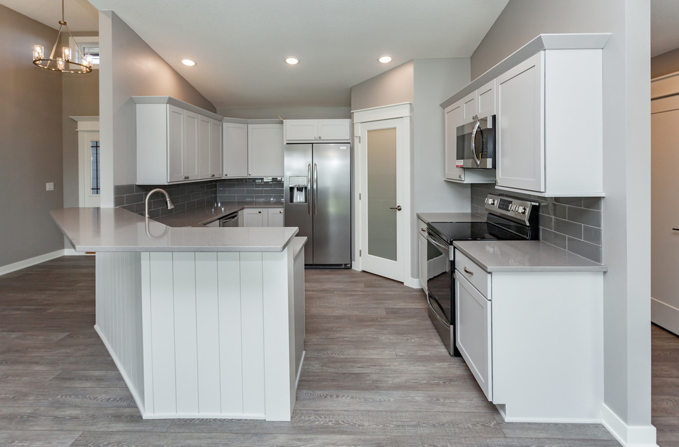 Kitchen - mid-sized transitional u-shaped medium tone wood floor and gray floor kitchen idea with an undermount sink, shaker cabinets, white cabinets, quartz countertops, gray backsplash, ceramic backsplash, stainless steel appliances, no island and gray countertops