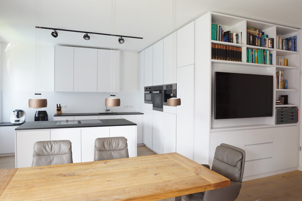 Photo of a mid-sized contemporary l-shaped kitchen in Cologne with an undermount sink, flat-panel cabinets, white cabinets, white splashback, porcelain splashback, panelled appliances, medium hardwood floors, with island, beige floor and grey benchtop.