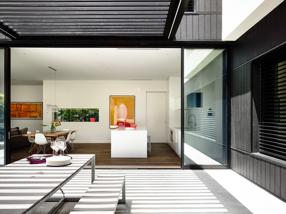 This is an example of a modern backyard patio in Melbourne with an outdoor kitchen, concrete slab and a pergola.