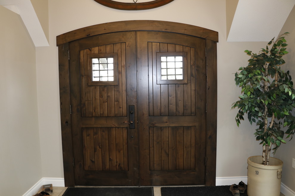 Mountain style ceramic tile and beige floor front door photo with beige walls and a dark wood front door