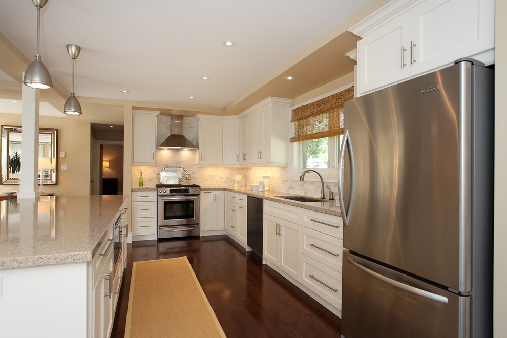 Photo of a mid-sized traditional galley eat-in kitchen in Toronto with an undermount sink, shaker cabinets, white cabinets, quartz benchtops, white splashback, subway tile splashback, stainless steel appliances, dark hardwood floors and with island.