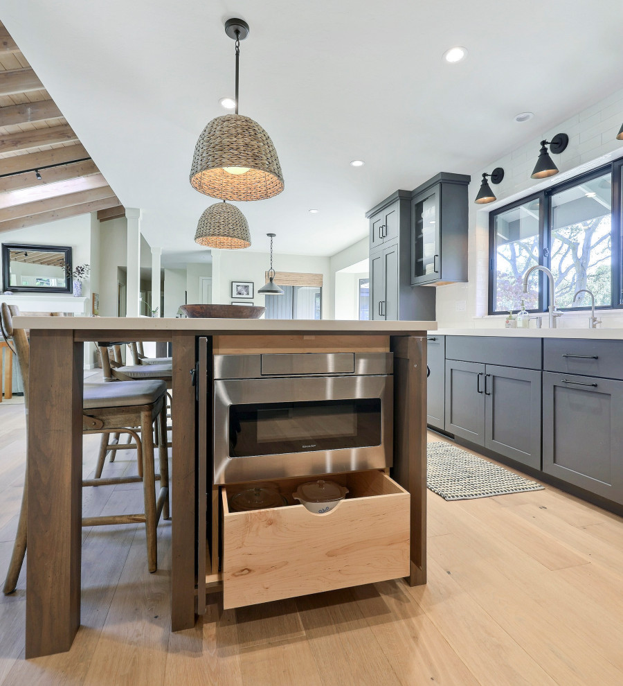 Open concept kitchen - mid-sized transitional l-shaped laminate floor open concept kitchen idea with a double-bowl sink, flat-panel cabinets, gray cabinets, quartz countertops, white backsplash, ceramic backsplash, stainless steel appliances, an island and white countertops
