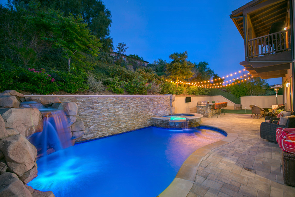 Inspiration for a mediterranean backyard custom-shaped natural pool in San Diego with a water feature and concrete pavers.